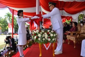 Gubernur sebagai Inspektur Upacara peringatan Hari Kemerdekaan RI ke-71 sedang menyerahkan bendera merah putih kepada Christi Mamoleh siswi SMA I Manado